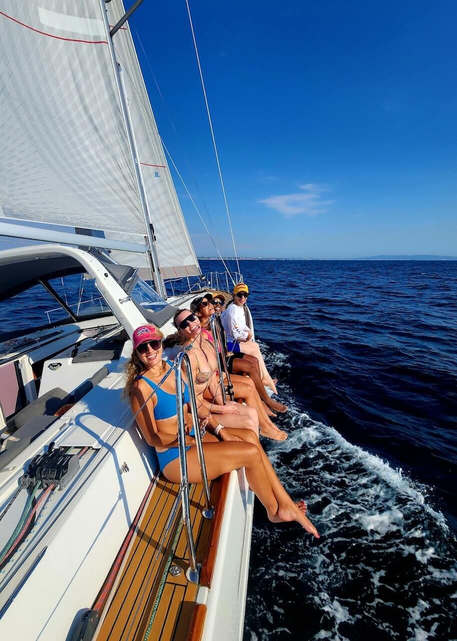 Group of friends sitting on the site of a sailboat while on a boat charter in Marina del Rey