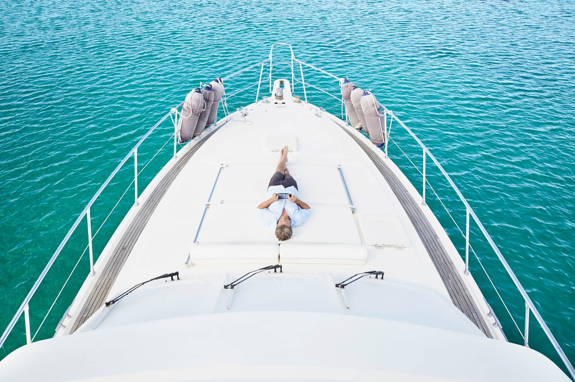 smiling man lying on deck of his motor yacht