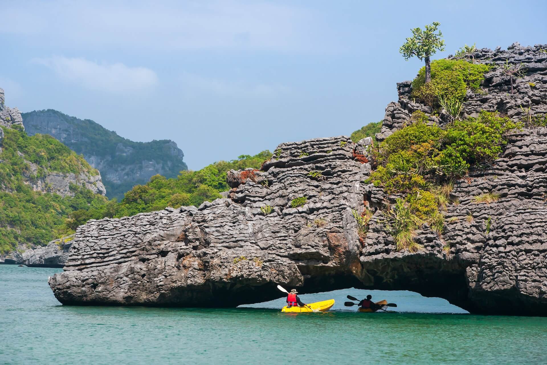 Kayaking in Channel Islands on a sunny summer day, with a natural stone bridge in the background.