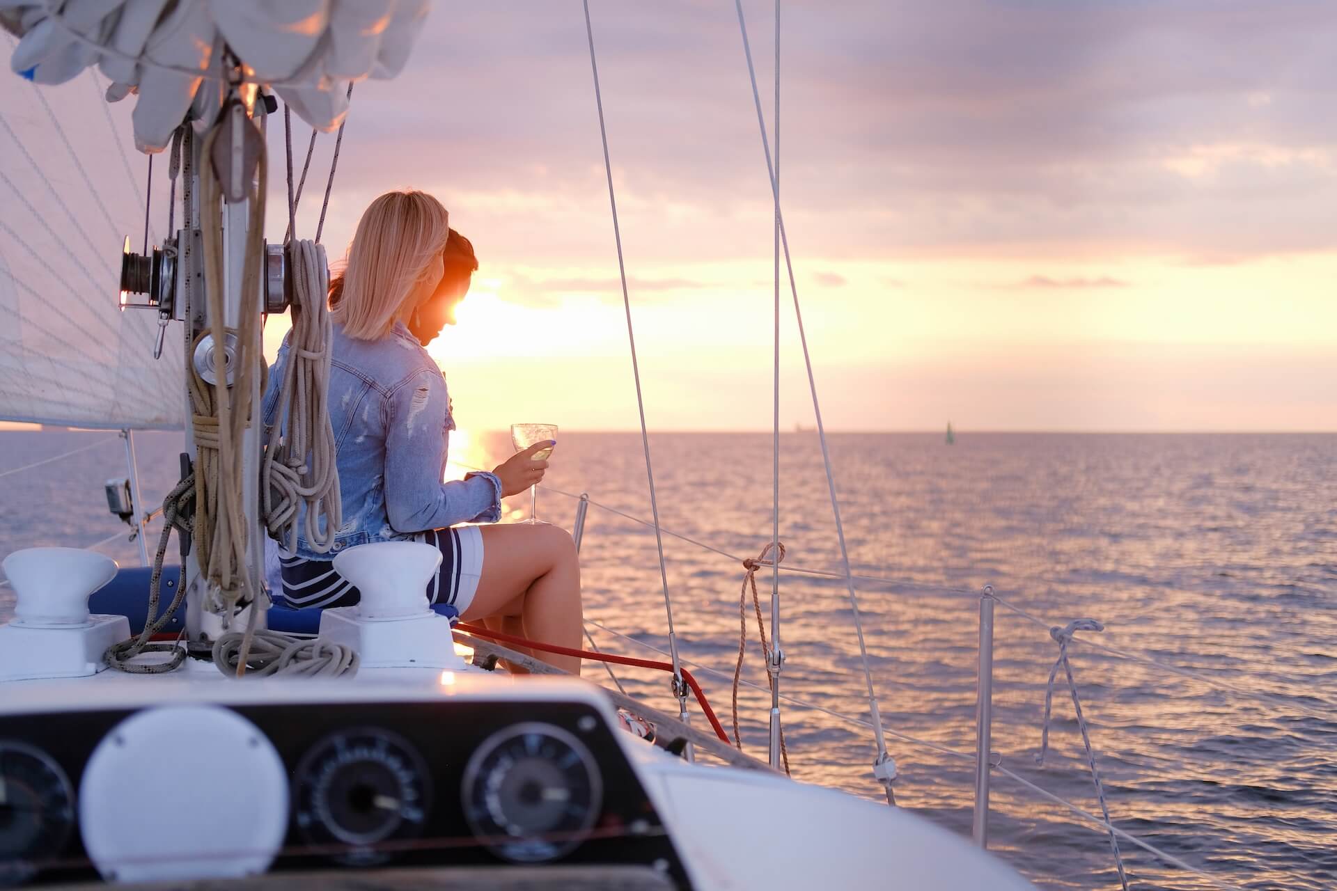 Two joyful women celebrating a summer day at the yacht while watching a beautiful sunset.