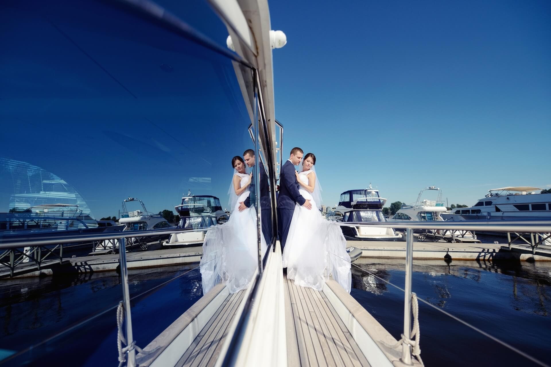 Wedding couple hugging on yacht, bride in dress and groom in suit