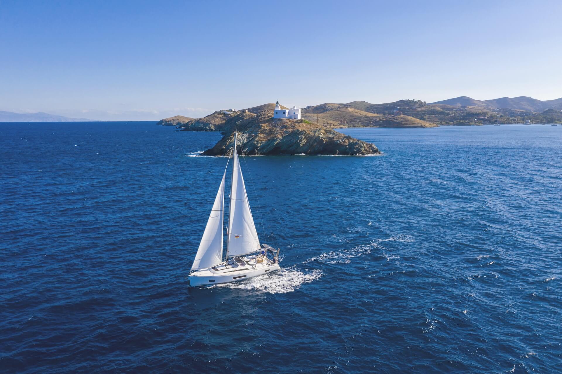 sailing boat with white sails rippled sea background